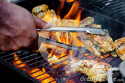 Chef cooking jerk barbecue BBQ chicken on the grill hand turning food Stock Photo