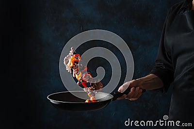 Chef cooking octopus seafood frying in a skillet with vegetables, freezing in motion Stock Photo