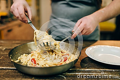 Chef cooking pasta, pan on wooden kitchen table Stock Photo