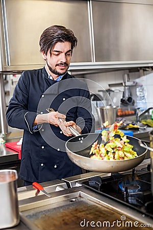 Chef cooking a vegetables stir fry over a hob Stock Photo