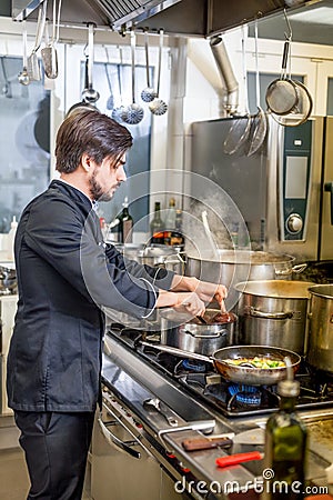 Chef cooking a vegetables stir fry over a hob Stock Photo