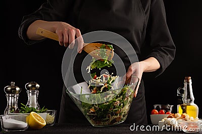 Chef cooks a salad, mixed on a black background. Cooking and home recipes Stock Photo