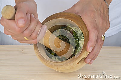 Chef crushing garlic and parsley with mortar and pestle in the k Stock Photo