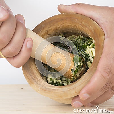 Chef crushing garlic and parsley with mortar and pestle in the k Stock Photo