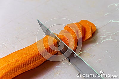 The chef cuts a carrot with a knife Stock Photo