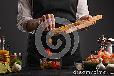 The chef cuts the cherry tomatoes and pours them out to make a shrimp salad. The business restaurant is preparing delicious and Stock Photo