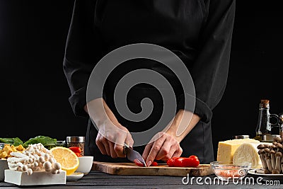The chef cuts cherry tomatoes to prepare a tasty and fresh salad. Vegetarian and fresh food, gastronomy and cooking, recipe book Stock Photo