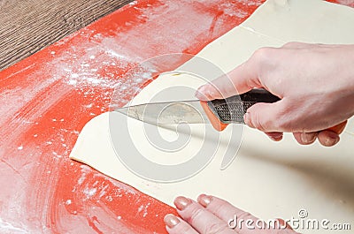 The chef cuts the dough with a knife Stock Photo