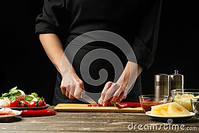 The chef cuts hot chilli peppers. For the preparation of pizza, salad. A delicious and spicy food concept, Mexican, cooking. On a Stock Photo