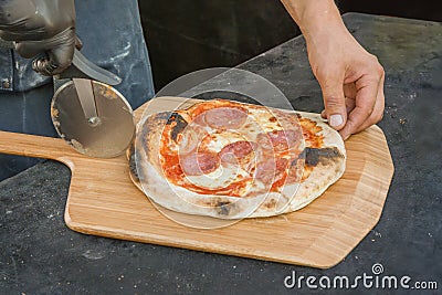 Chef cuts the pizza into pieces with a special knife. Stock Photo