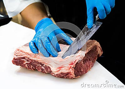 Chef cuts raw meat with a knife on a board, Cook cuts raw meat Stock Photo