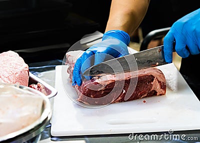 Chef cuts raw meat with a knife on a board, Cook cuts raw meat Stock Photo