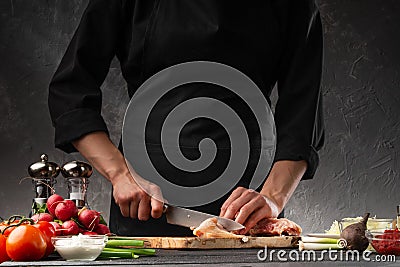 Chef cutting chicken meat, ingredients for cooking on a background of vegetables. Culinary recipes, cookbooks Stock Photo