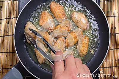 Chef frying chicken wings in pan Stock Photo