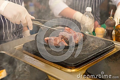 Chef frying meat in a wok over a griddle Stock Photo