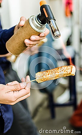 A chef grilling cheese with a kitchen gas torch at a food market Stock Photo