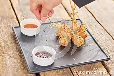 Chef hand adding sesame to fried shrimps. Stock Photo