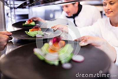 Chef handing appetizer plate through order station Stock Photo