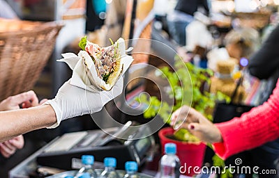 Chef handing a tortilla to a foodie at a street food market Stock Photo