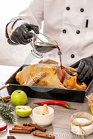 Chef hands cooking duck with oranges and apples on white kitchen background. add soy sauce. Food concept Stock Photo