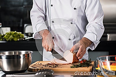 Chef hands slice meat at kitchen restaurant. Closeup chef hands cutting hum. Stock Photo