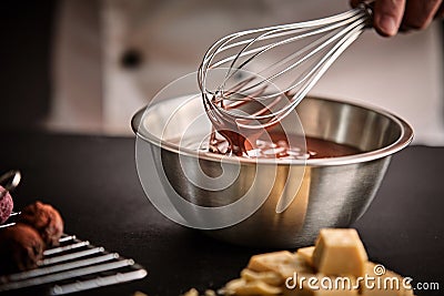 Chef holding a whisk with melted chocolate Stock Photo