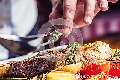 Chef in hotel or restaurant kitchen cooking only hands. Prepared beef steak with vegetable decoration Stock Photo