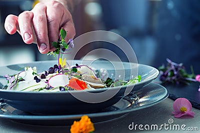 Chef in hotel or restaurant kitchen cooking, only hands. He is working on the micro herb decoration. Preparing vegetable salad Stock Photo