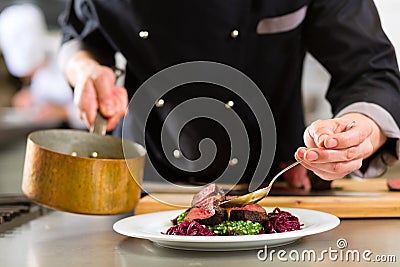 Chef in hotel or restaurant kitchen cooking Stock Photo