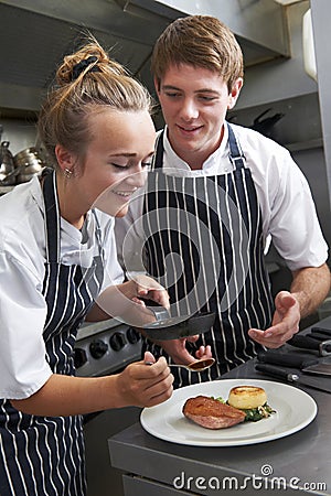 Chef Instructing Trainee In Restaurant Kitchen Stock Photo