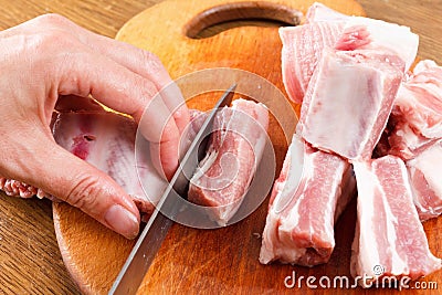 Chef knife cuts raw pork ribs on a cutting board Stock Photo