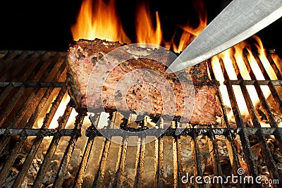 Chef Knife in the Grilled Meat Chop. Flame in Background. Stock Photo