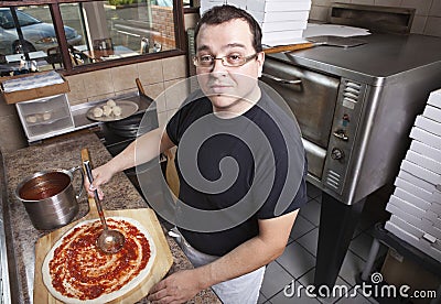 Chef making a pizza spreading sauce Stock Photo