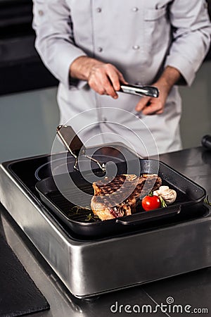 Chef man prepare steak at griddle pan. Closeup chef hand cooks grill beef. Stock Photo