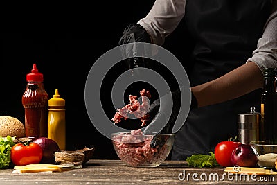 The chef mixes fresh ground beef, to create a burger patty. Against the background with ingredients for a burger. Gastronomy, Stock Photo