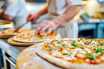 The chef in the pizzeria kitchen decorates a delicious pizza with mozzarella and basil Stock Photo