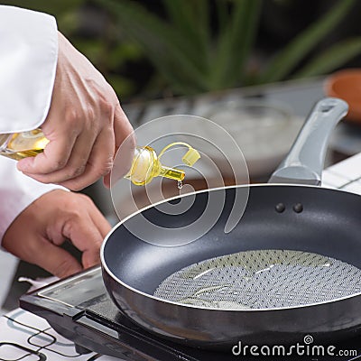 Chef pouring vegetable oil to the pan Stock Photo