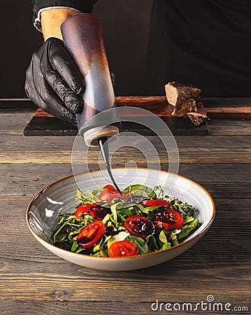 Chef pours sauce on the salad dish Stock Photo