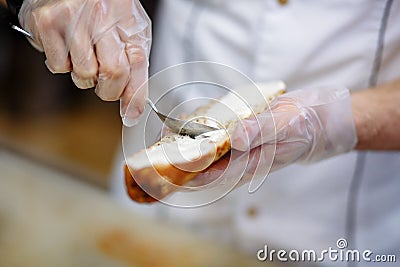 Chef prepares a baguette with salmon, hands in polyethylene gloves Stock Photo