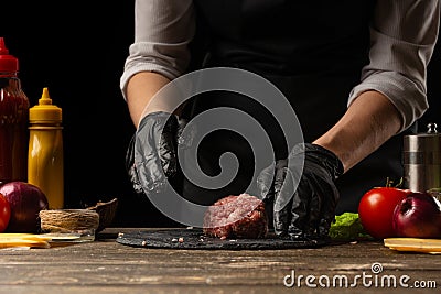 The chef prepares beef patty, with ingredients in the background, restaurant business, fast food, tasty food, gastronomy, cooking Stock Photo