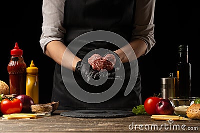 The chef prepares the cutlet with fresh ground beef, holding in the form of a heart, ingredients on the background, cooking a Stock Photo