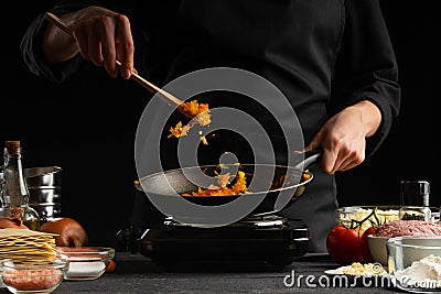 The chef prepares Italian lasagna, against the background of ingredients. Black background. Delicious and healthy food, restaurant Stock Photo