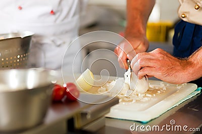 Chef preparing onion in restaurant or hotel kitchen Stock Photo