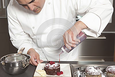 Chef Puts Finishing Touches On Chocolate Cake At Kitchen Counter Stock Photo