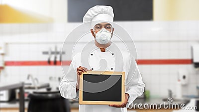 Chef in respirator with chalkboard at kitchen Stock Photo