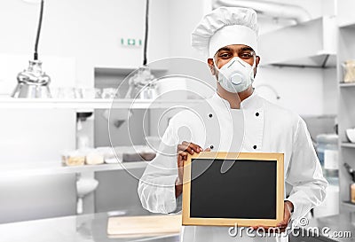 Chef in respirator with chalkboard at kitchen Stock Photo