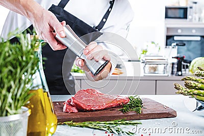 Chef in restaurant kitchen cooking,he is cutting meat or steak Stock Photo