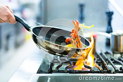 Chef in restaurant kitchen at stove with pan Stock Photo