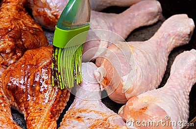 The chef`s hand with a brush spreads the chicken meat with spices and prepares the ingredients for cooking Stock Photo