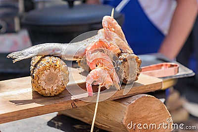 Chef serves wooden desk with seafood and sweet grilled corn at the festival. Street food prepared on grill Stock Photo